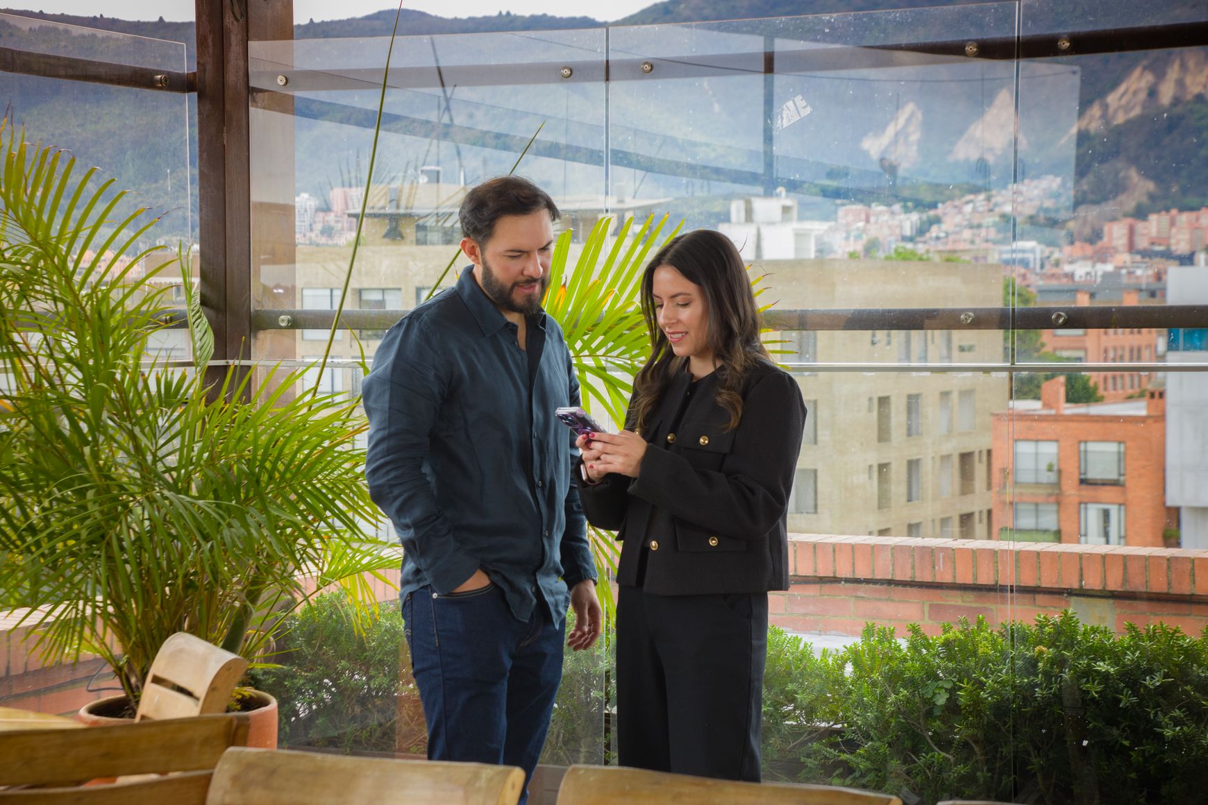 Dos clientes de Eva revisando un celular en la terraza con vista a los cerros